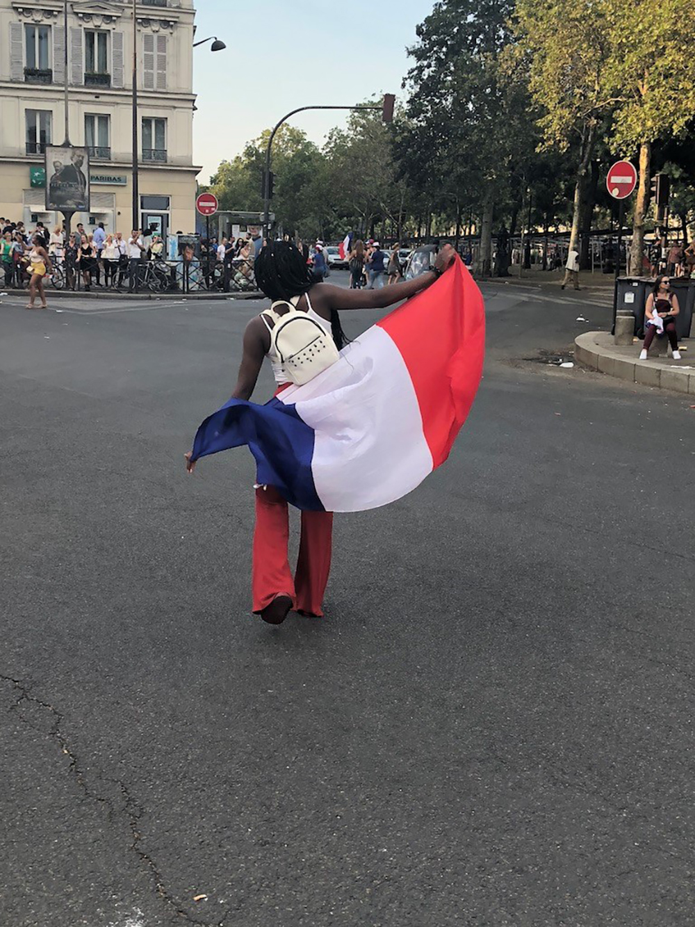 A person walking in the street with the French flag
