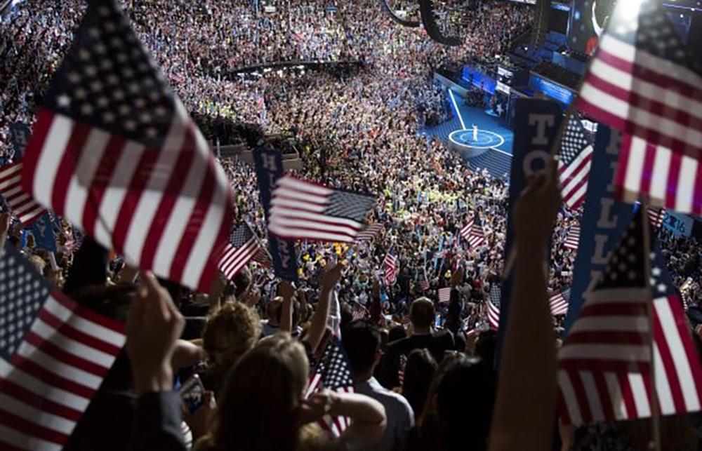 A large audience holding American flags
