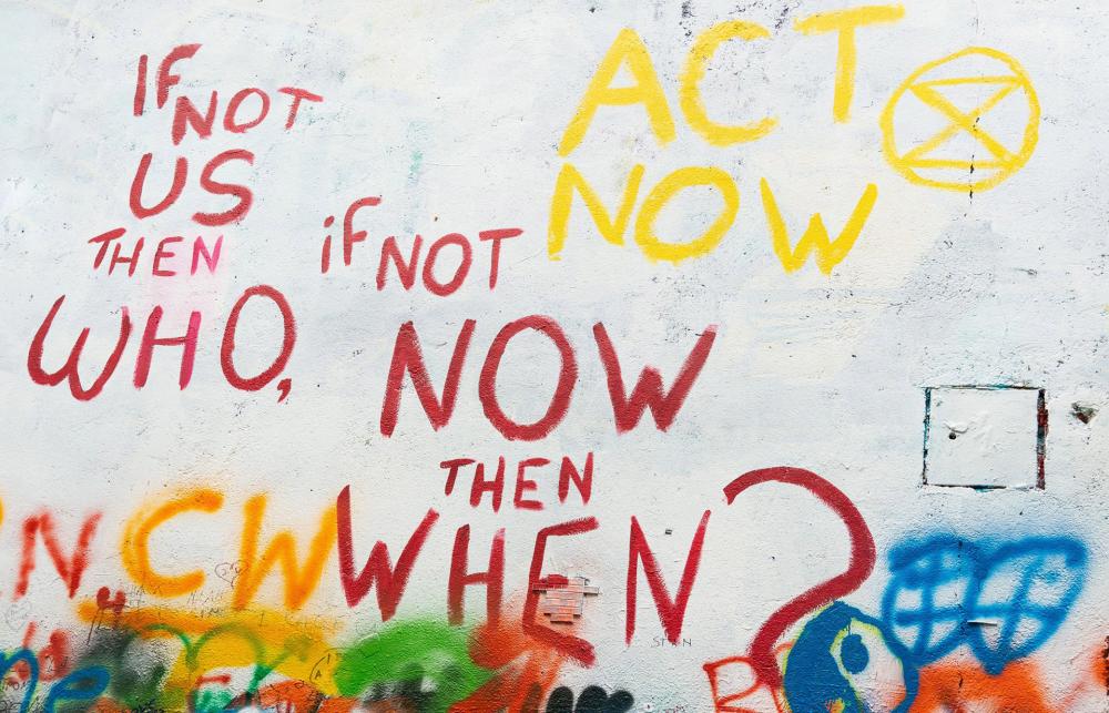 Graffiti reads: If not us then who, if not now then when. Act now.