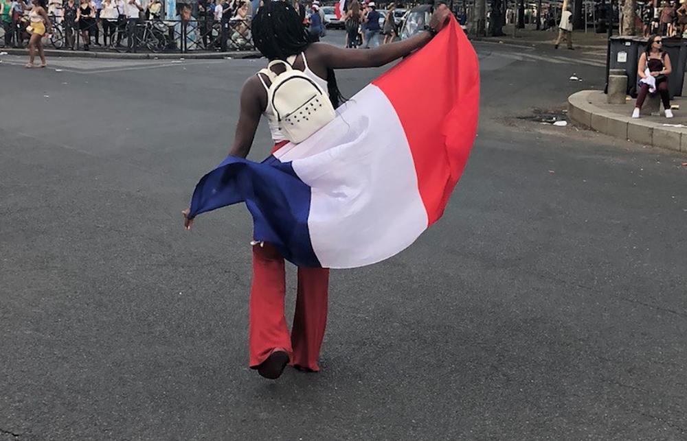 A person walking in the street with the French flag